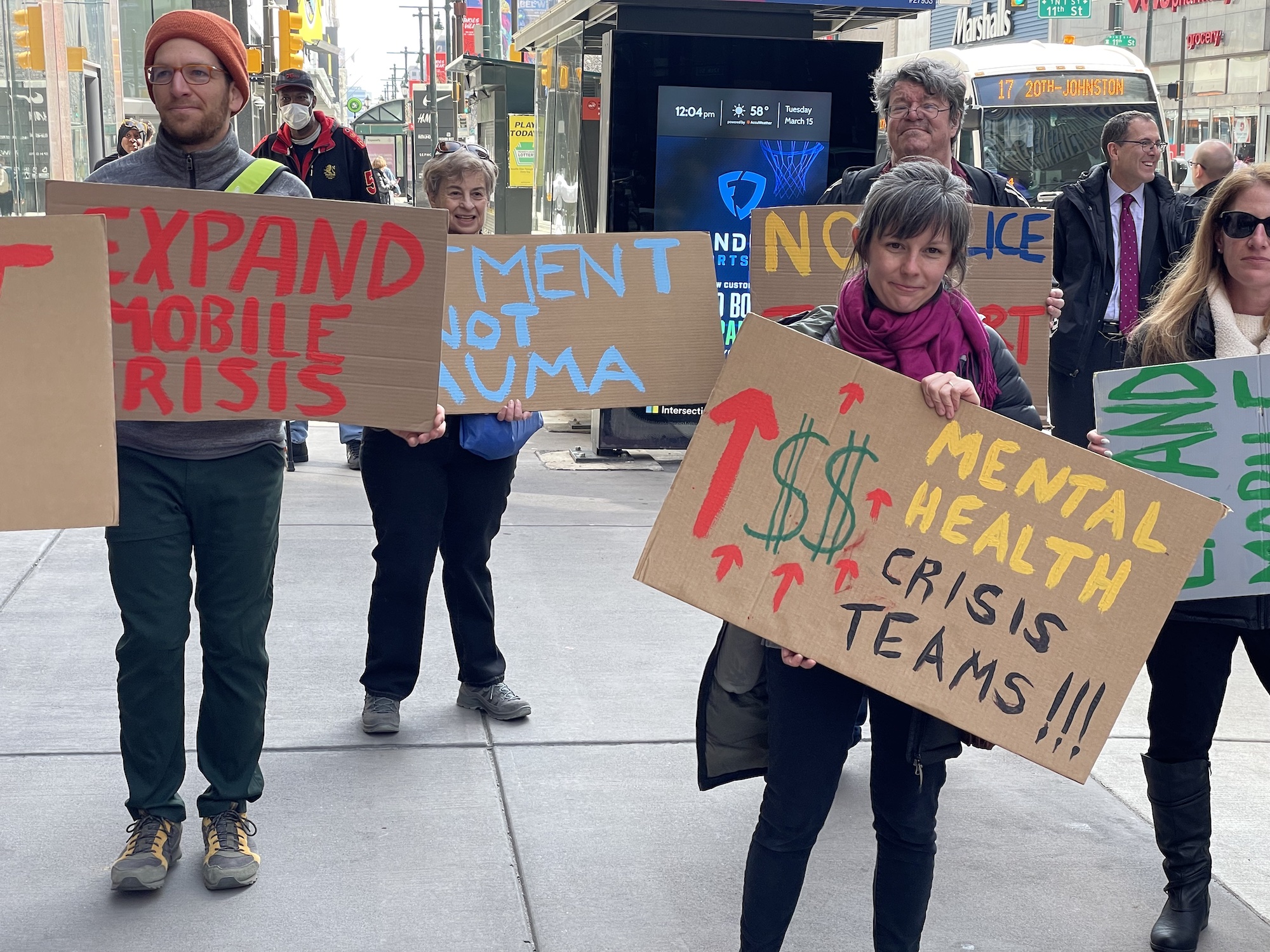 a crowd holds signs calling for mobile crisis response