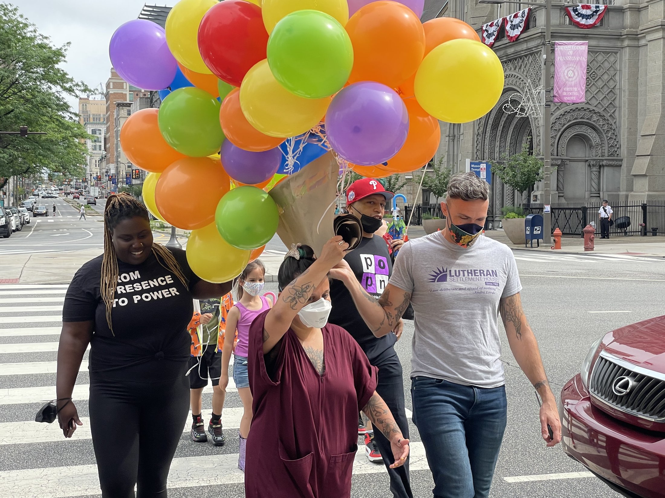 A crown of people walks with colorful balloons