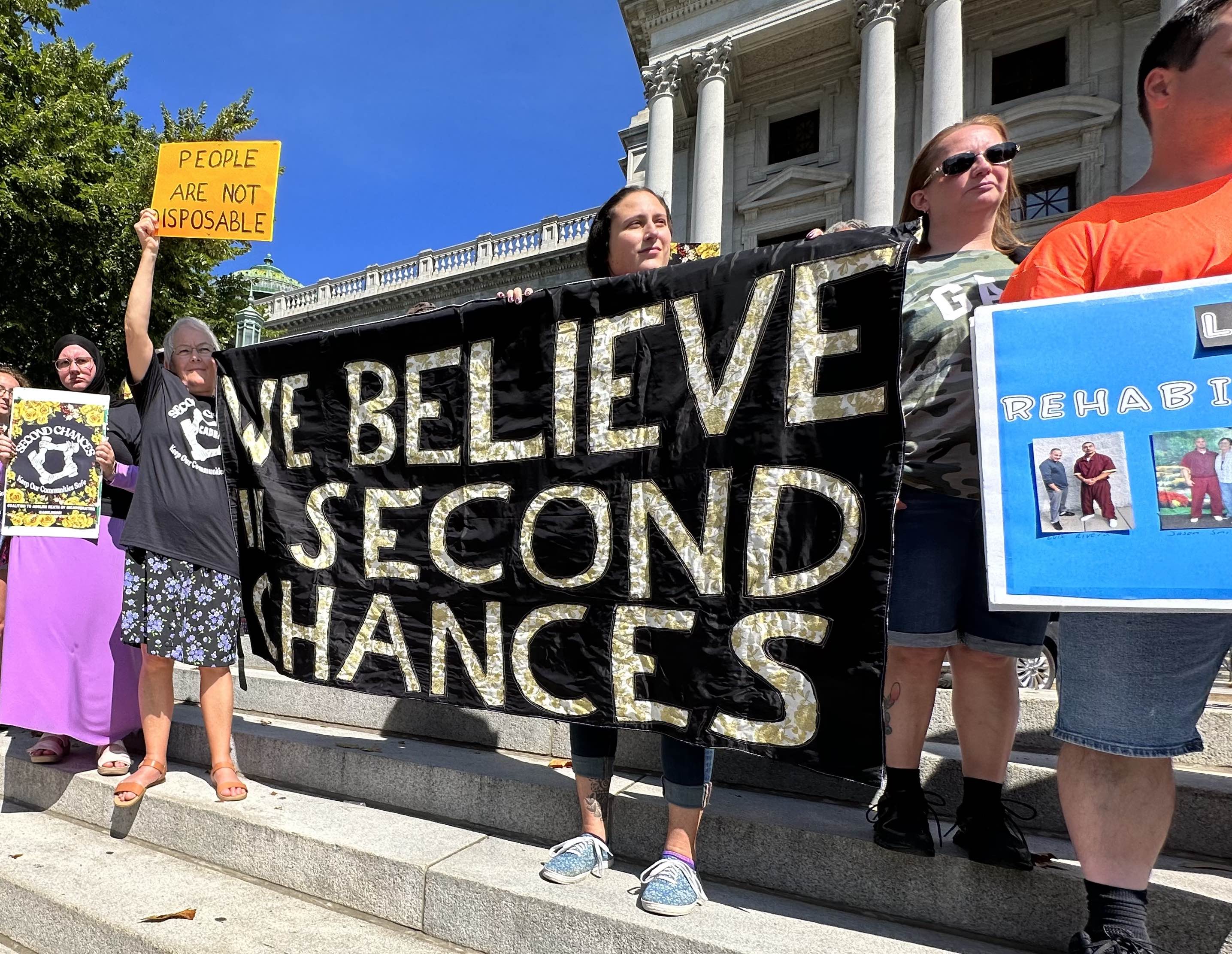 People stand with a banner that says We Believe in Second Chances
