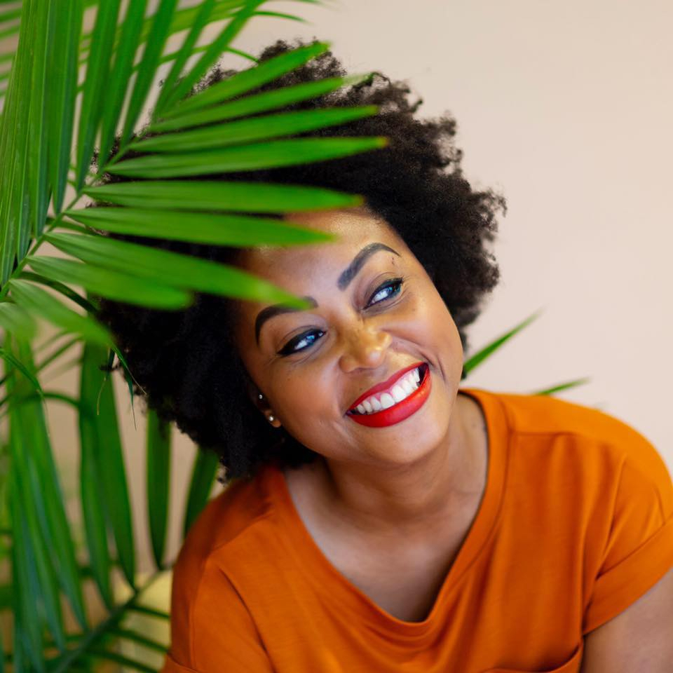 an image shows Stephanie Keane smiling with a plant in the background