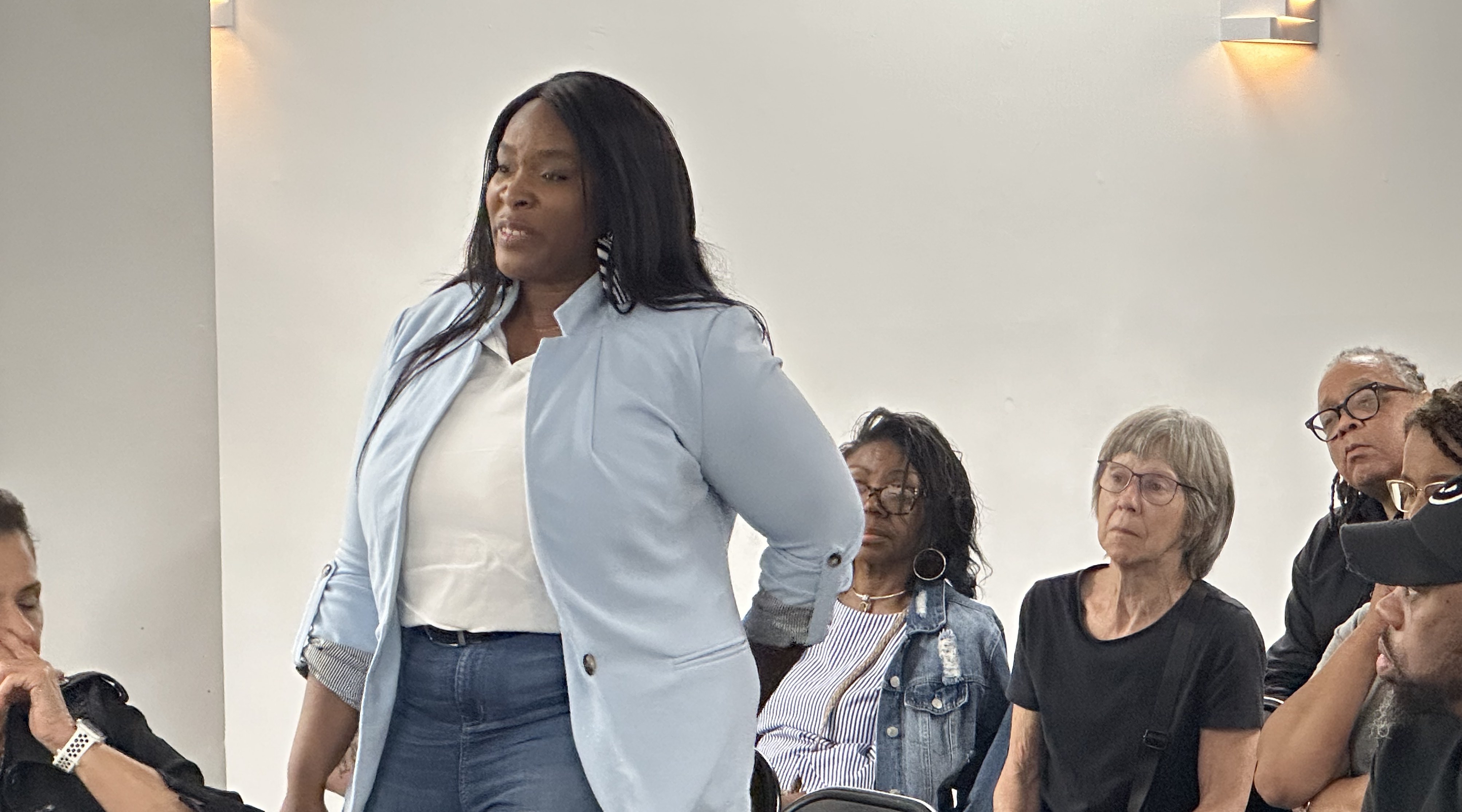 A woman in a blu shirt stands up as she is speaking to the panel's