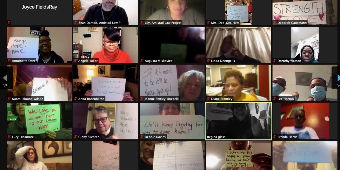 A screenshot of a zoom meeting shows people holding up signs with messages of hope and liberation