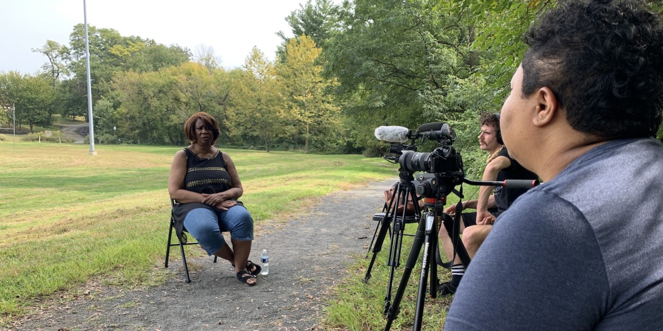 Kris Henderson sits as a video crew interviews Yvonne Newkirk about what she would like to see funded instead of the police