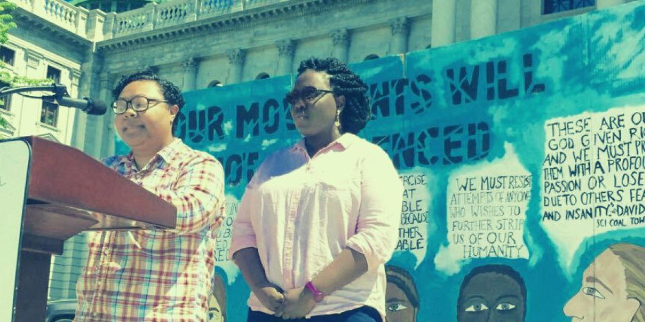 Kris Henderson and Nikki Grant stand at a podium with the words Black Feminism for Liberation underneath