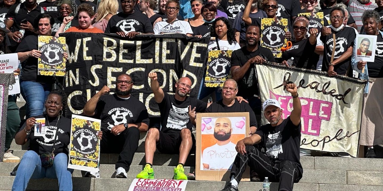 People pose on the Harrisburg capitol steps with a banner that reads We Believe in Second Chances