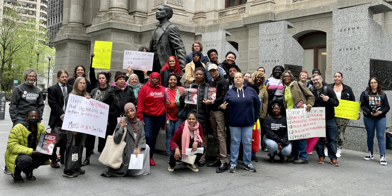 Family members of incarcerated people and advocates hold signs in front of Cato Statue at City Hall