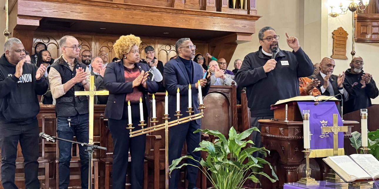 Bishop Dwayne Royster speaks as a members of the assembled Coalition to Defend Democracy applaud