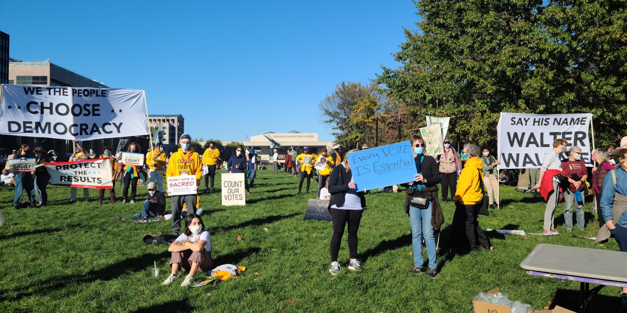 people gathered holding signs "We the People Choose Democracy" and "Say His Name Walter Wallace" prominently featured