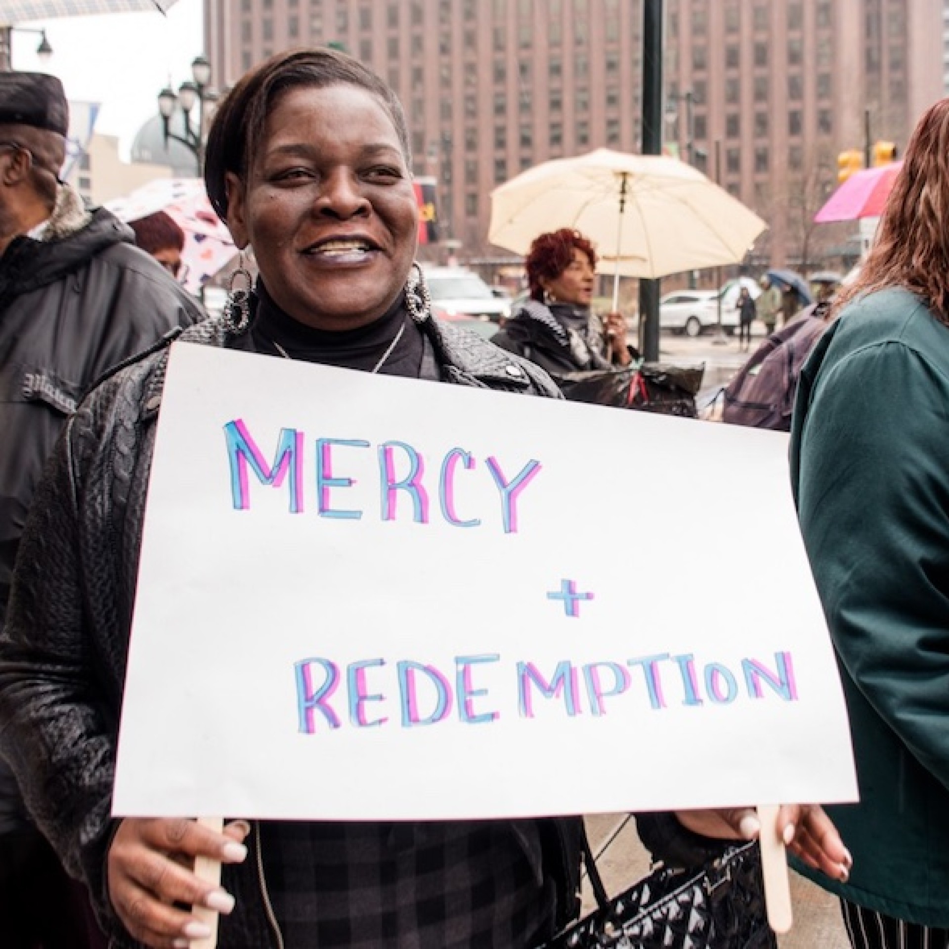 Marthea Brown holds a sign that says Mercy and Redemption