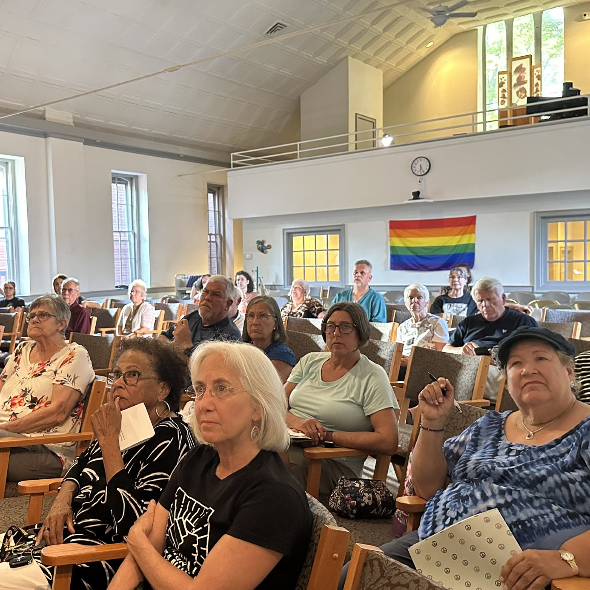 An audience watches No Way Home with a rainbow flag hanging on the back wall