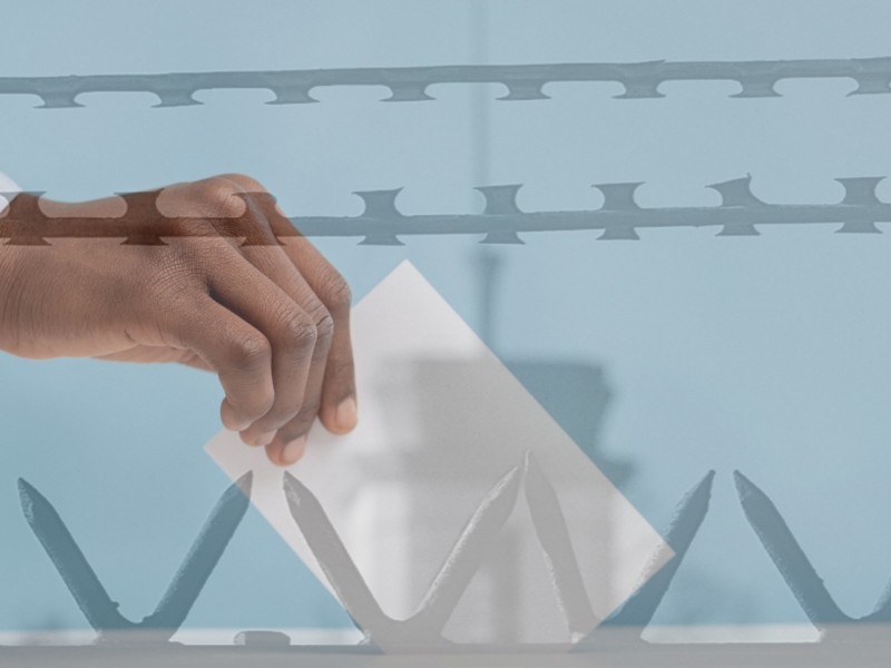 an image shows a Black person's hand putting a ballot into a ballot box juxtaposed with barbed wire