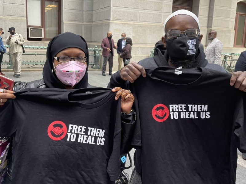 Shamar and Shymita two members of Free Them to Heal Us hold up t-shirts at a rally for geriatric parole