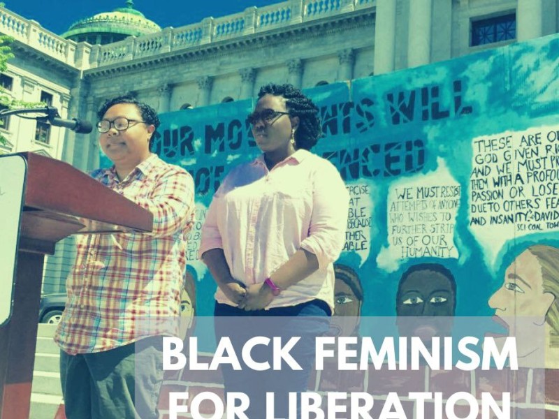 Kris Henderson and Nikki Grant stand at a podium with the words Black Feminism for Liberation underneath