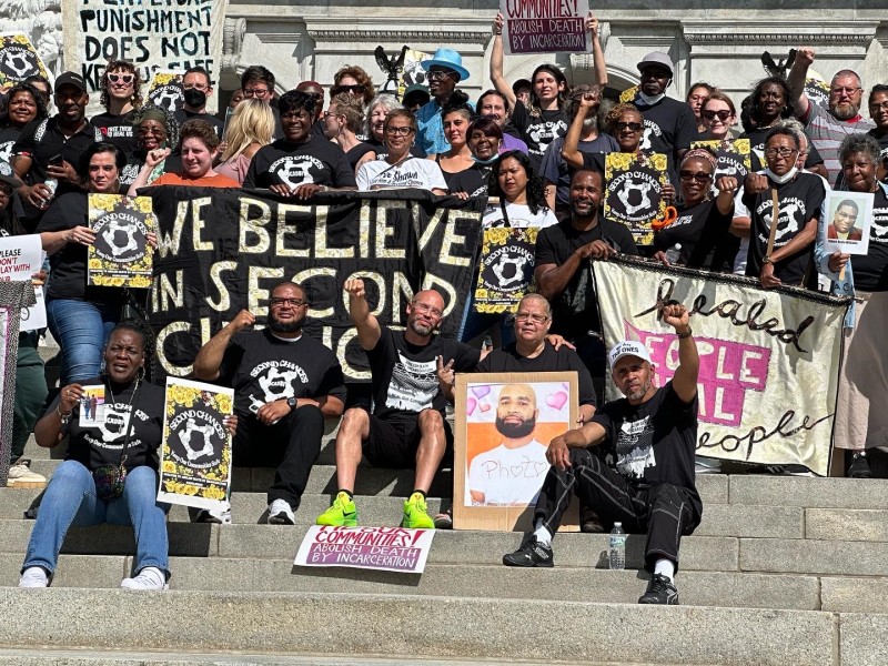 People pose on the Harrisburg capitol steps with a banner that reads We Believe in Second Chances