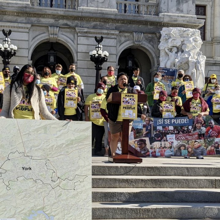 Amistad Law Project Executive Director Stands at a podium speaking  surrounded by people in yellow shirts in front of the state capitol building in Harrisburg