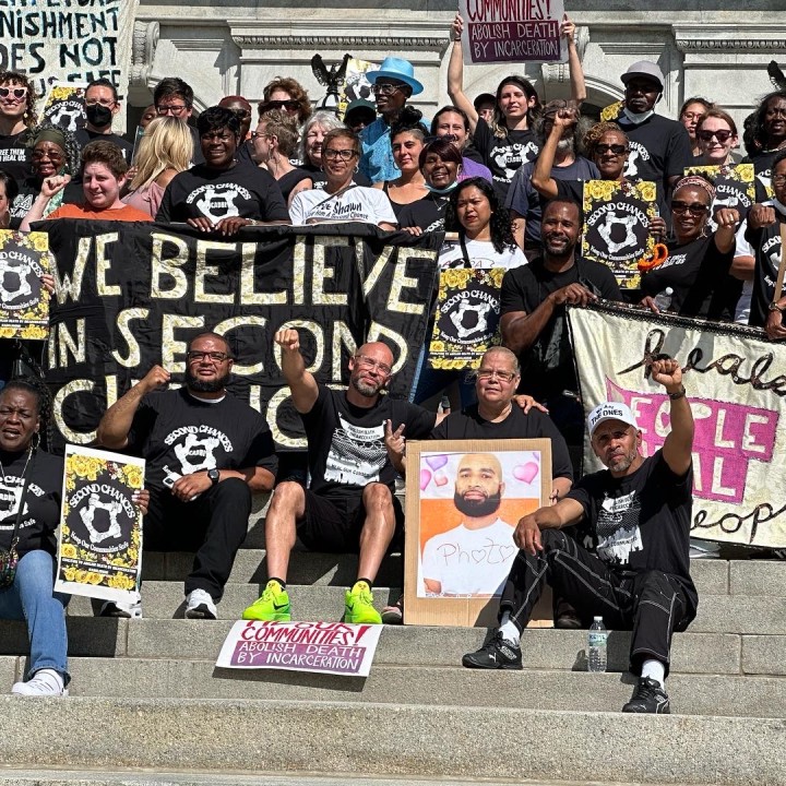 People pose on the Harrisburg capitol steps with a banner that reads We Believe in Second Chances