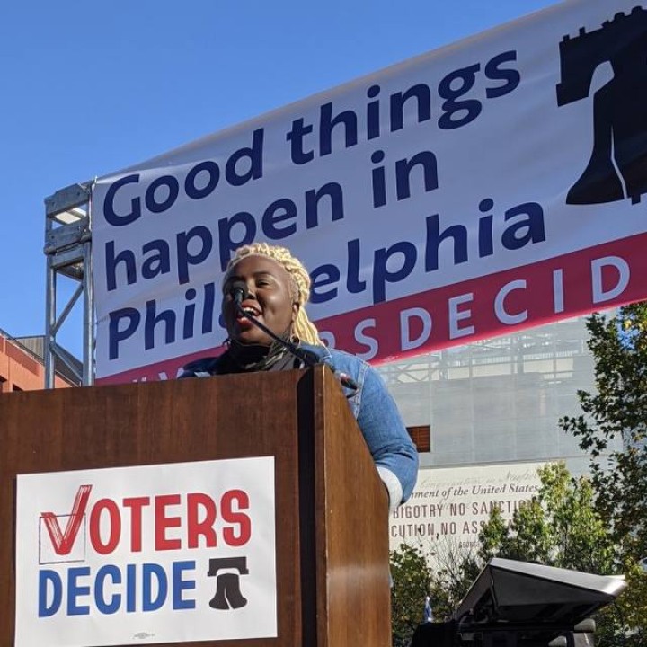 Nikki Grant speaks at a podium with a sign on it that says Voters Decide